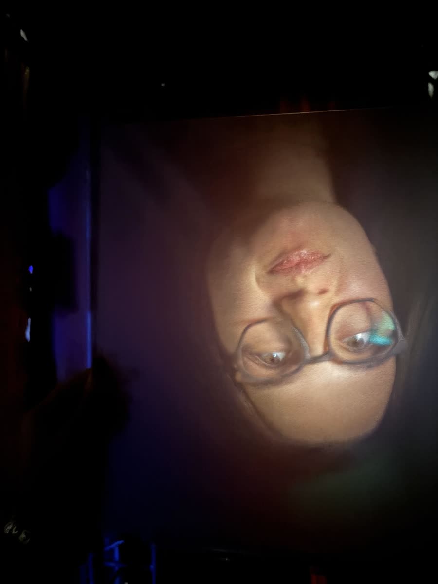 Inverted image of a face on acrylic in a dark room